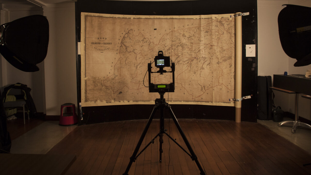 A large Tithe map is hung from a magnetic wall, with a digital camera set up in front of it.